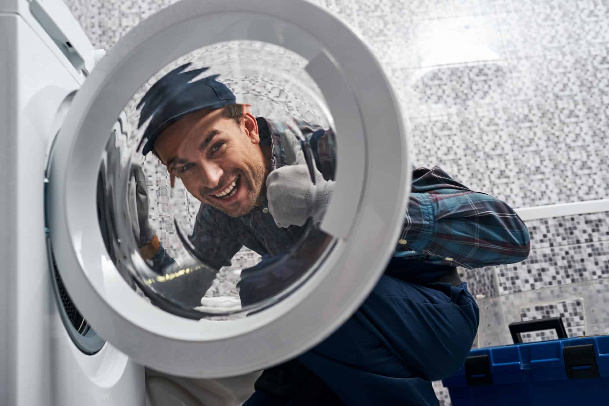 glad of own results working man plumber in bathroom checking washing mashine